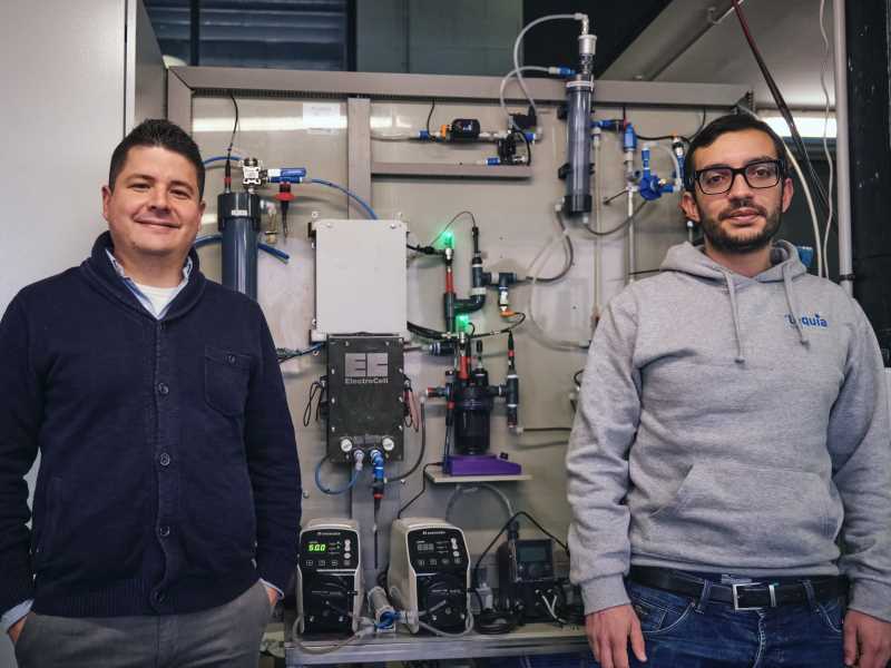 Luis López (esquerra) i Paolo Dessi (dreta) als laboratoris del grup de recerca LEQUIA, davant d'una planta pilot d'electrosíntesi microbiana