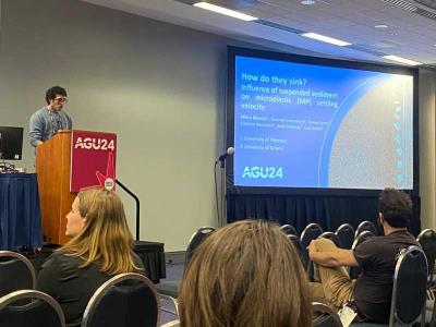 Photograph of Researcher M. Mancini Presenting at AGU24 on Microplastic Settling Dynamics